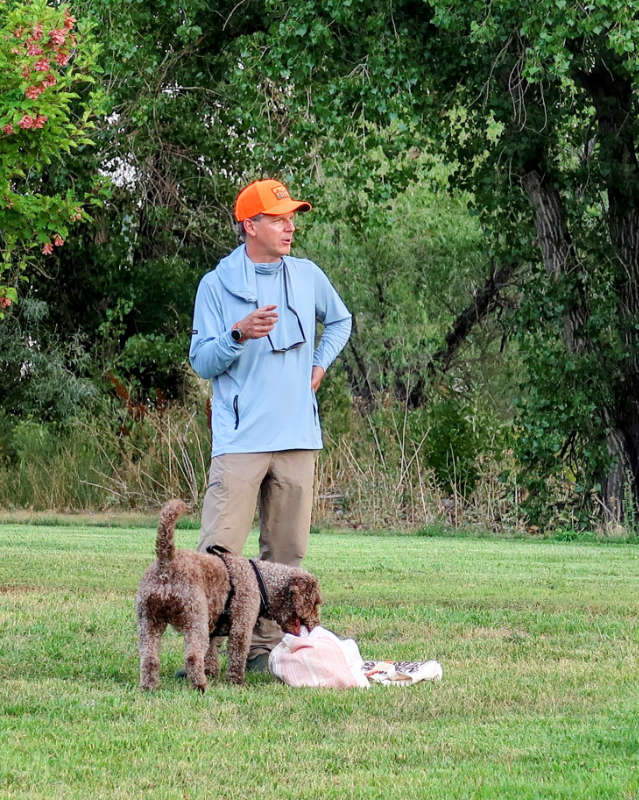 A Spanish Water Dog with a man in an orange hunting cap. They are Paco and Arthur Morgan.